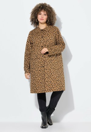 Cappotto a stampa leopardo in marrone e nero, con chiusura a bottoni, maniche lunghe e due tasche anteriori. Abbinato a pantaloni neri e stivali.