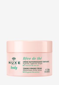 Hellrosa Dose der Nuxe Rêve de thé Körpercreme mit grünem Text, 200 ml, zeichnet sich durch eine glatte Textur und ein schlichtes, modernes Design aus.