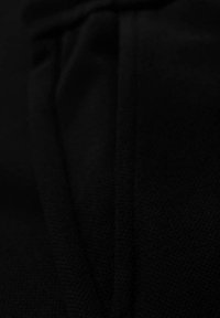 Tissu noir avec un tricot texturé et des coutures pliées en diagonale.