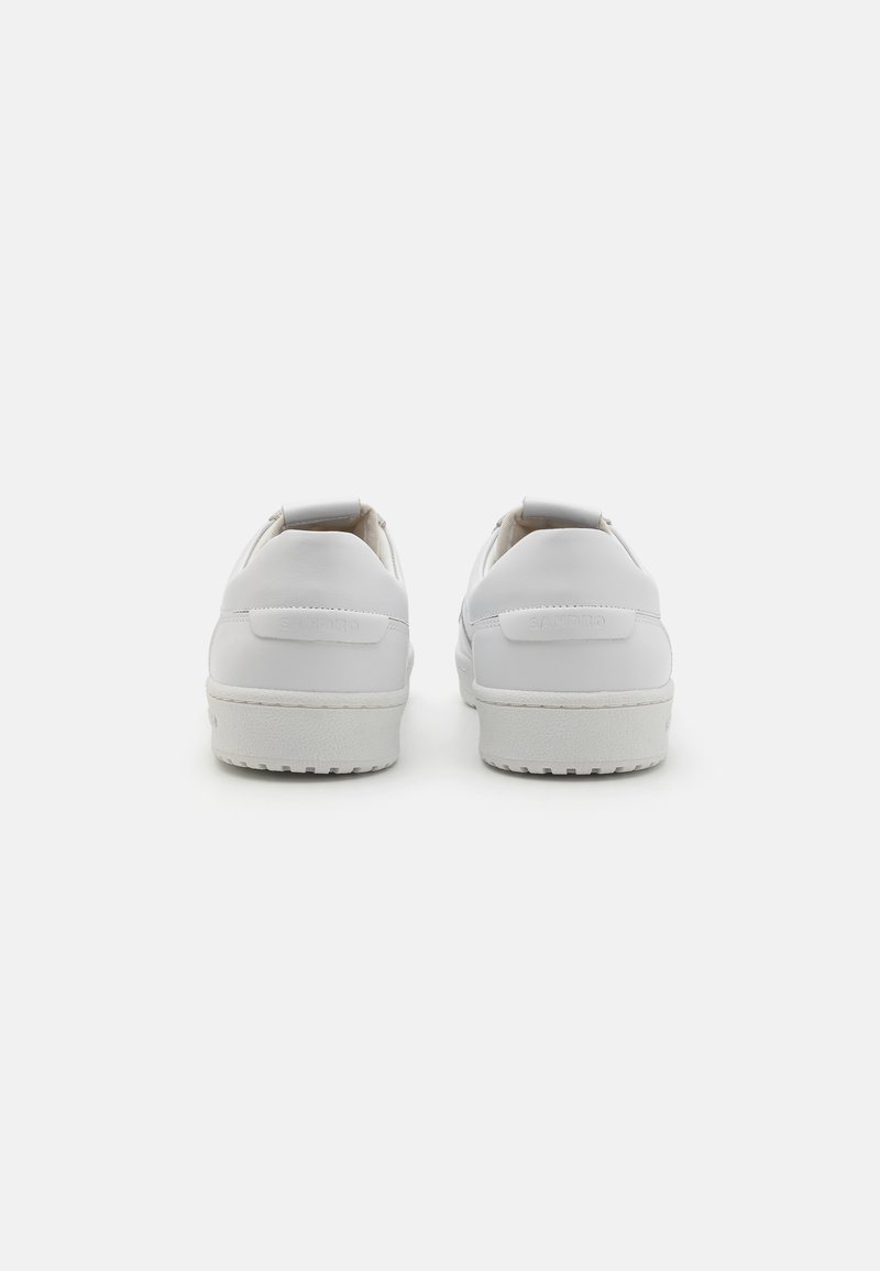 White leather sneakers with a smooth finish, rounded toe, flat sole, and subtle brand logo on the heel. Minimalistic design without embellishments.
