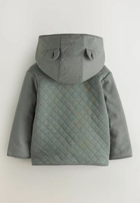 Quilted grå jakke med en tekstureret ryg, flad hætte og rundede ører. Stoffet er blødt med en glat front og diamantmønster.