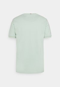 T-shirt vert clair à manches courtes avec un col rond, fabriqué en tissu doux, présentant une texture subtile et un accent en blocs de couleur sur le col arrière.