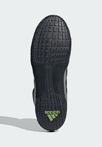 Black athletic shoe sole featuring a textured rubber surface, rectangular patterns, and a green Adidas logo. Reinforced sides in black.
