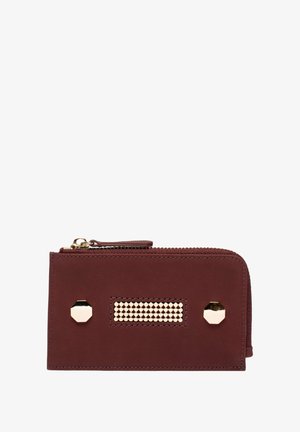 Portefeuille en cuir bordeaux avec des accents en métal doré, fermeture éclair, forme rectangulaire et panneau décoratif clouté à l'avant.
