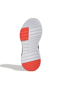 Podešev boty s texturovaným bílým gumovým základem, s červeným akcentem v oblasti paty a vroubkovaným vzorem pro lepší přilnavost.