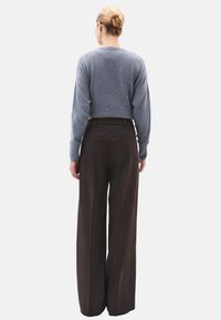 Grijze cropped trui met lange mouwen, gecombineerd met hoog getailleerde, wijde bruine broek met zakken en een gladde textuur.