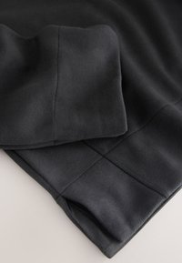 Schwarzer Baumwollpullover mit glatter Textur, weichem Finish und gerippten Bündchen, sichtbaren Nähten und schlichten Design.