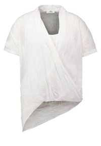 Blouse blanche à manches courtes avec col en V, devant cache-cœur et ourlet asymétrique, réalisée en tissu léger légèrement texturé.