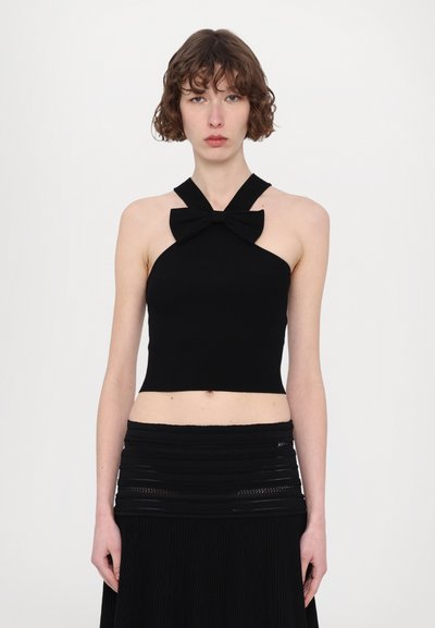 Haut court noir à col halter côtelé avec un détail en nœud au niveau du cou. Le tissu est lisse et ajusté, mettant en valeur la silhouette.