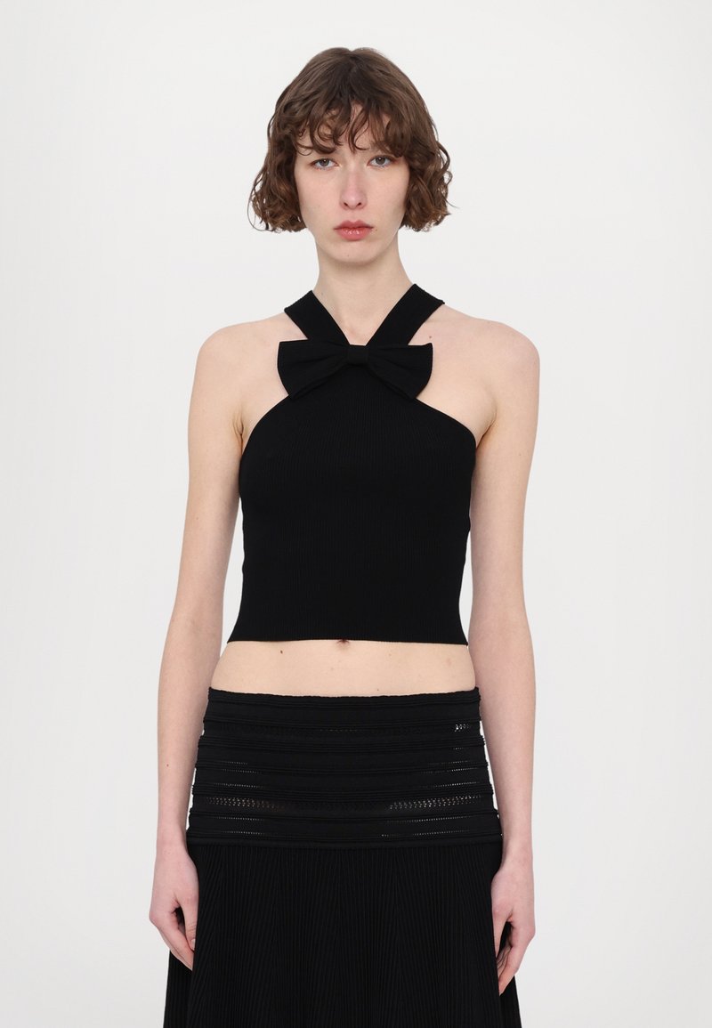Zwarte geribbelde halter crop top met een strikdetail bij de nek. De stof is soepel en aansluitend, waardoor de silhouet wordt benadrukt.