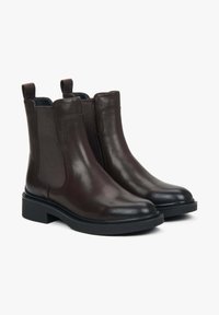 Hnědé kožené chelsea boty s elastickými bočními panely a poutky. Hladký povrch, zaoblená špička a robustní černá gumová podrážka.