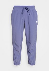 Pantalon de sport lilas en tissu léger, doté d'une ceinture élastique avec cordon de serrage, de jambes fuselées et d'un petit logo blanc.