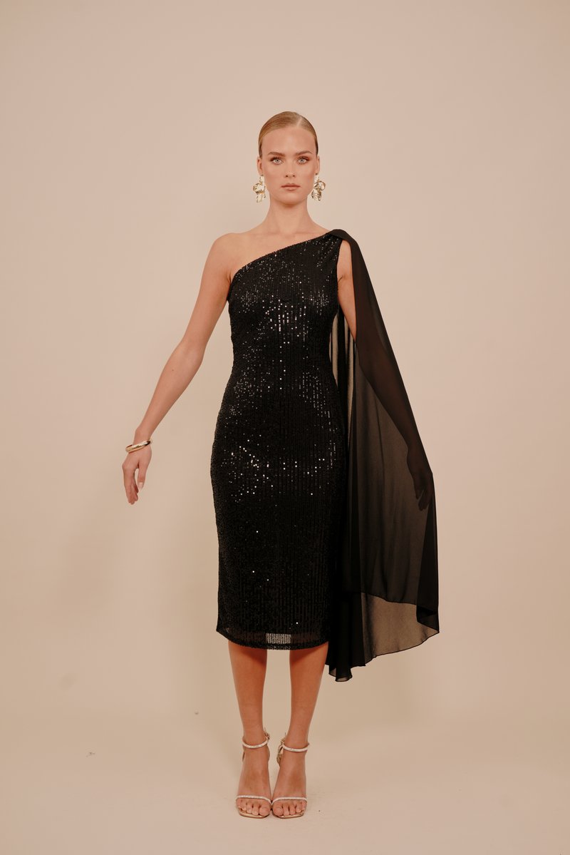 Fekete flitteres koktélruha egyik vállánál, valamint légies fekete átlátszó anyaggal. Ezüstszínű pántos magassarkú cipőkkel és elegáns karkötővel kiegészítve.