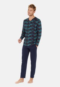 Langärmliges navy-blaues Oberteil mit einem bunten Muster aus Bergwellen, kombiniert mit einfarbigen navy-blauen Hosen. Weicher Stoff, lockere Passform und gerades Bein Design.