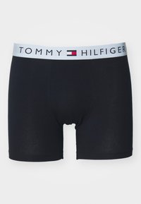 Boxeri din bumbac negri cu un brâu elastic de culoare bleu deschis, având logo-ul "TOMMY HILFIGER" și accente roșii și albe.