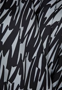 Schwarzer Stoff mit abstrakten, gezackten grauen Mustern; glatte Textur mit leichtem Glanz, gefaltet, um das Design zu zeigen.