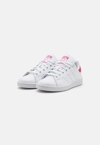 Vita lädersneakers med rosa detaljer, rund tå, snörning framtill, perforerade sidor och texturerad gummisula. Klassisk design med varumärke på tungan.