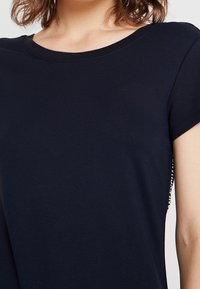 Mörkblå kortärmad t-shirt i mjukt material, med rund halsringning och mönstrade sidodekorationer, i en avslappnad passform.