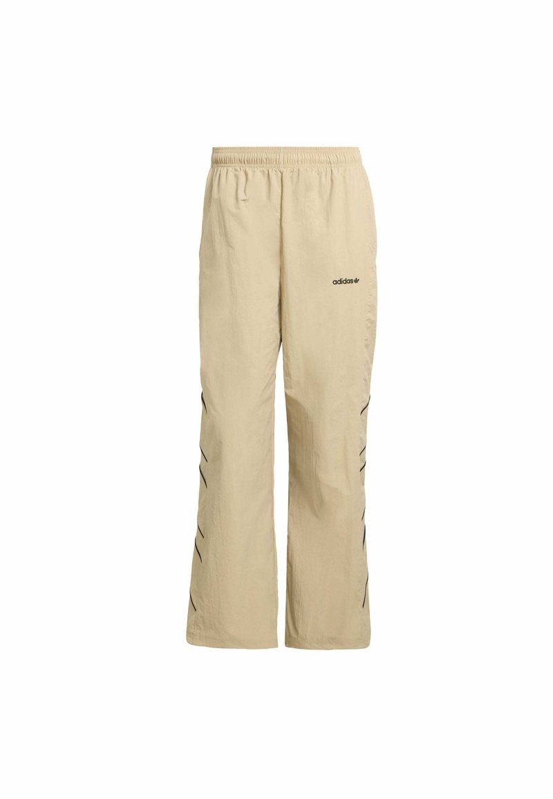 Pantaloni sportivi beige con vita elastica, vestibilità ampia, caratterizzati da accenti a zigzag neri lungo il lato e un logo Adidas stampato vicino all'anca.