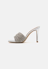 Sandale à talons hauts argentée avec une bride texturée et froncée, un design à bout ouvert et un talon métallique élégant. Semelle intérieure lisse avec des accents doux en tan.