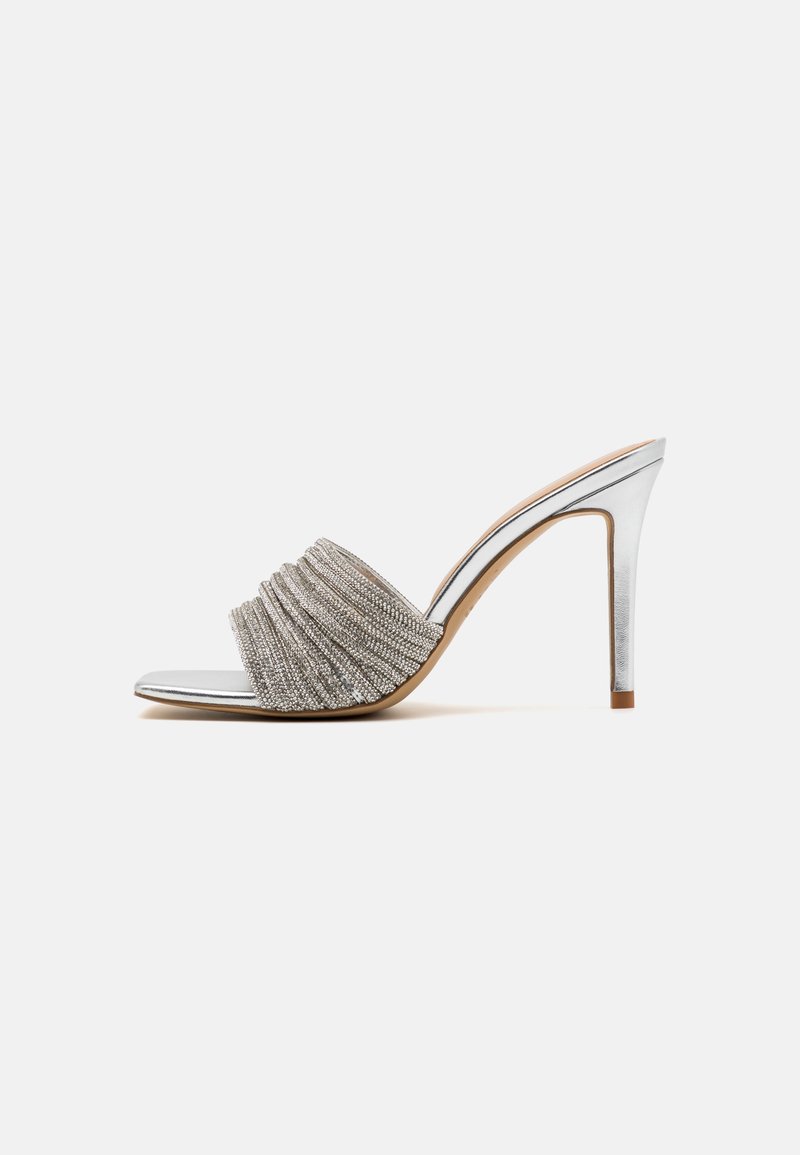 Sandale à talons hauts argentée avec une bride texturée et froncée, un design à bout ouvert et un talon métallique élégant. Semelle intérieure lisse avec des accents doux en tan.