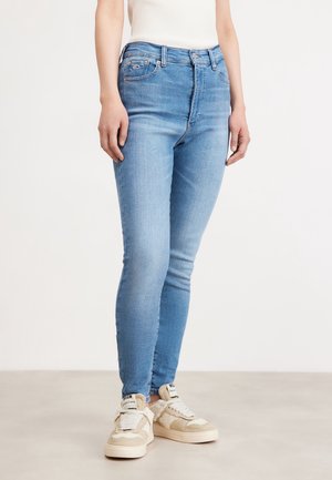 Jeans skinny de tiro alto en azul claro, hechos de denim, con cinco bolsillos, ligero desgaste y cierre de cremallera con botón.