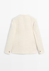 Witte textuurjas met een rechte snit, lange mouwen en een knoop aan de manchet. De achterkant heeft een subtiele verticale naaddetail.