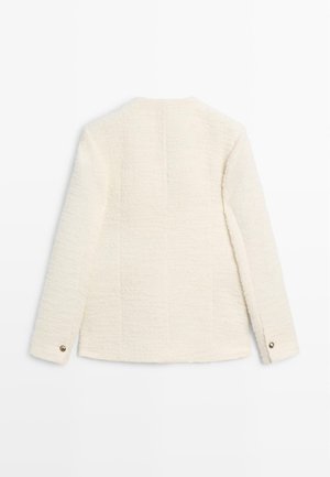 Hvid tekstureret jakke med lige snit, lange ærmer og en knap ved manchetterne. Bagsiden har en diskret lodret sømdetalje.