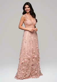 Lång rosa klänning med en figurnära spetsliv, genomskinlig flödande kjol, 3D-blommor och intrikata detaljer på tyget.