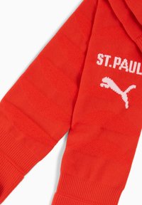 Czerwona dzianina z fakturowanymi falistymi wzorami oraz białym napisem "ST. PAULI" obok białego logo Puma.