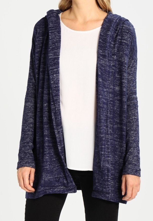 Cardigan aperto di colore blu navy, con una texture, cappuccio e maniche lunghe. Indossato su una camicia bianca, che mette in risalto la sua vestibilità ampia e rilassata.