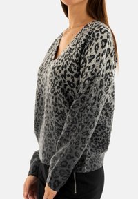 Maglione grigio a maglia con scollatura a V, stampato con macchie di leopardo nere e polsini a coste. Il design sfuma da tonalità più chiare a tonalità più scure.
