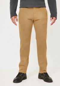 Tan pants with a smooth texture, straight fit, and standard pockets, paired with black lace-up shoes and a dark gray sweater.