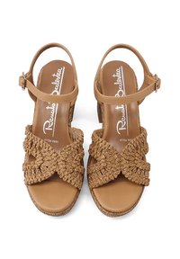 Sandali piatti color sabbia con tomaia in tessuto intrecciato, design incrociato, cinturino alla caviglia e punta aperta. Suola con texture e dettagli intrecciati.