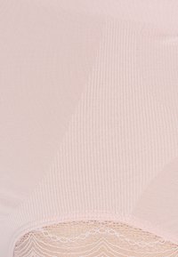 Vêtement sans couture rose clair présentant une texture côtelée. Le bord inférieur présente des détails en dentelle délicats avec un motif en dentelle.