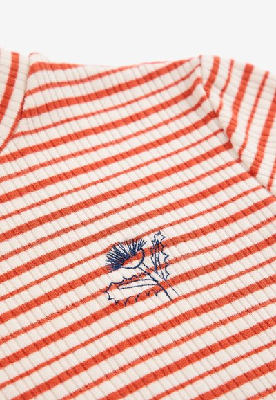 Gros plan sur un tissu blanc côtelé avec des rayures orange horizontales et une fleur de chardon brodée bleue au centre.