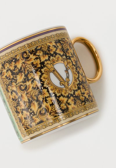 Λευκό και χρυσό κεραμικό κύπελλο με περίπλοκο μοτίβο χρυσού φύλλου και αμπελουργικό σχέδιο, με διακοσμητικό κυκλικό έμβλημα και χρυσή λαβή.