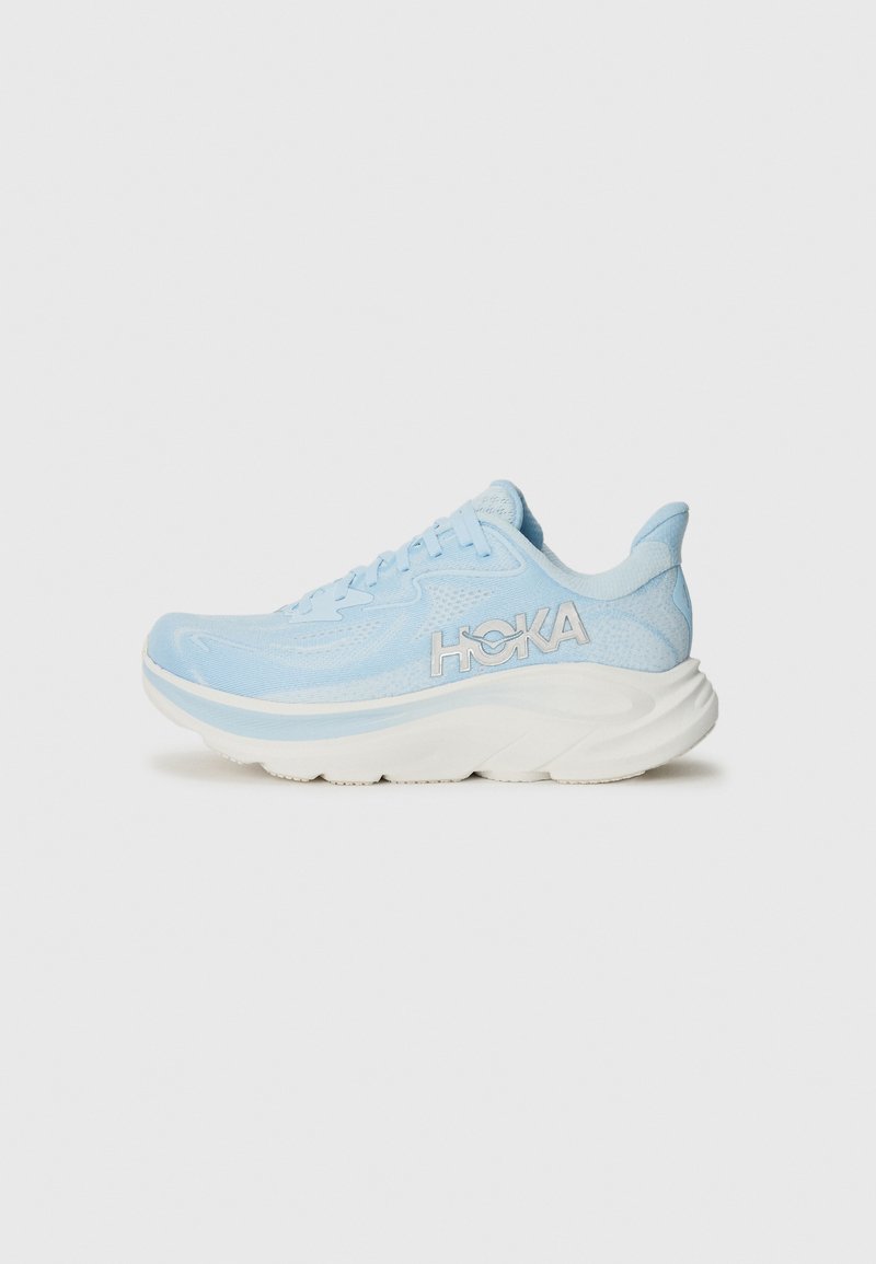 Light blue athletic shoe with mesh upper, cushioned white midsole, and prominent logo on the side. Features round laces and textured accents.