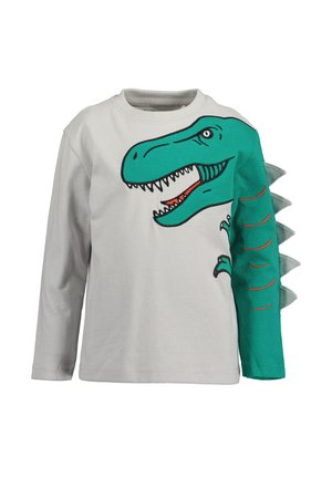 Biała koszula z długim rękawem z zieloną twarzą i ramieniem dinozaura, z materiałowymi kolcami wzdłuż prawego rękawa.