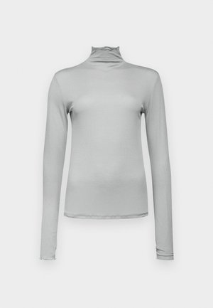 Svetlo siva dolgi rokav turtleneck iz gladkega, raztegljivega materiala. Oprijet kroj z visokim ovratnikom in diskretnim nagubanjem ob robu.