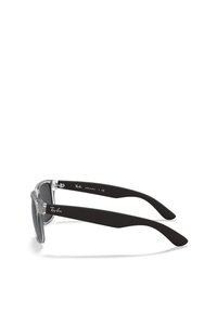 Occhiali da sole con montatura frontale trasparente, aste nere opache e lenti scure; presenta il logo Ray-Ban sul braccio e un design distintivo.
