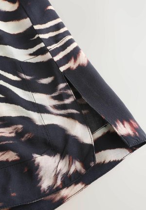 Black fabric with a fluid texture features a pink and cream abstract pattern. Side slit detail at hem adds dimension to the garment.