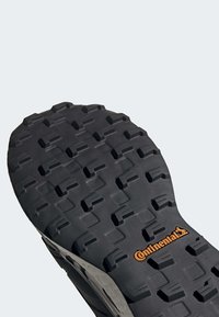 Semelle de chaussure avec des crampons profonds et multidirectionnels et le logo "Continental" en orange, conçue pour une meilleure adhérence et durabilité.