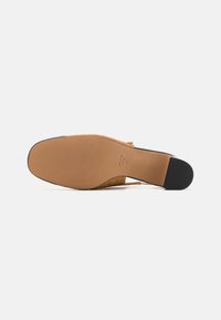 Woven tan slide sandal with a flexible rubber sole. Features a textured finish and an open back design for easy wear.