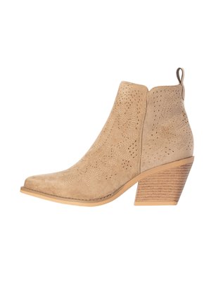 Beige suède enkellaarsje met blokhak, decoratieve perforaties en lipje aan de achterkant.