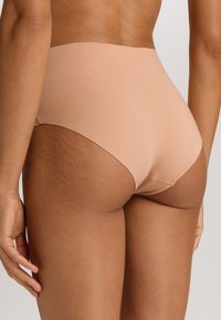Vysoké béžové spodní pradlo, hladká tkanina, bezešvý design, středně vysoký zadní díl, elastický materiál, žádné viditelné linie kalhotek.