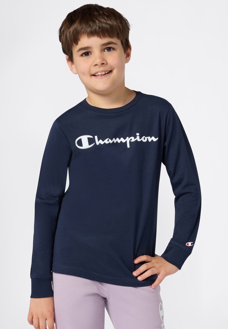 Marineblaues Langarm-T-Shirt mit weißem "Champion"-Logo, Rundhalsausschnitt, weicher Stoff, mit einem roten und weißen Logo-Akzent am Ärmel. Lässiger Schnitt.