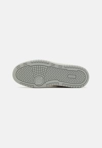 Grey rubber sneaker sole with textured grip patterns, circular accent, and distinct treads for traction. Flat design suitable for casual wear.