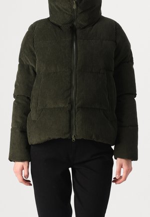 Donkergroene corduroy doorgestikte jas met rits aan de voorkant, lange mouwen en hoge kraag, gedragen met zwarte broek door een persoon die staat.