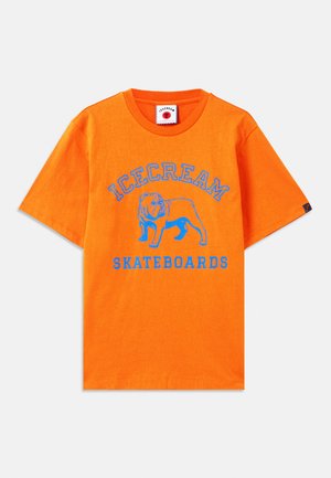 Orange bomulds T-shirt med korte ærmer, der har et blåt grafik af en løve og tekst som siger "ICECREAM SKATEBOARDS." Standard rund hals.